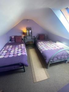 2 Betten in einem Dachzimmer mit violetter Bettwäsche in der Unterkunft Ceecliff flat in Culdaff