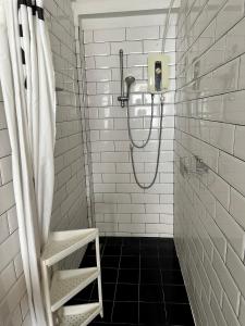 a shower with a hose in a white tiled bathroom at The Cute Silom hostel in Bangkok +83 photos