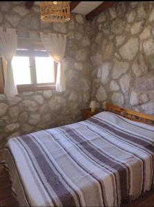 een slaapkamer met stenen muren, een bed en een raam bij Cabaña de piedra Los Crespines in San Antonio de Arredondo +8 foto's