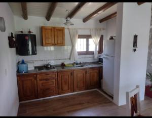 een keuken met houten kasten en een witte koelkast bij Cabaña de piedra Los Crespines in San Antonio de Arredondo