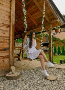 a woman in a white dress sitting on a swing at Drinska Villa Cabin in Perućac