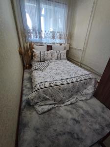 a small bedroom with two beds and a window at Уютная квартира in Taraz