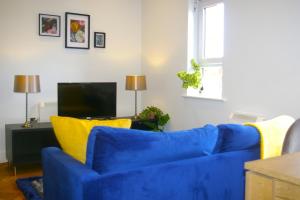 a living room with a blue couch and yellow pillows at The Hornblower Suite - Yorkshire Accommodates in Ripon
