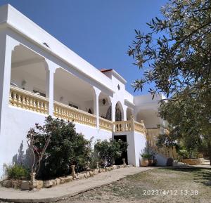 uma casa branca com uma varanda ao lado em Domaine des Sloughis em Meknès