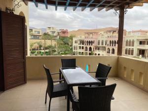 einen Tisch und Stühle auf einem Balkon mit Blick auf die Gebäude in der Unterkunft Tala bay aqaba one bedroom nice view in Al Burj