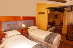 a hotel room with two beds and a mirror at Hotel La Posada de San Antonio in Villa de Leyva