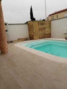 una piscina con suelo de baldosa y un edificio en Maison cosy avec piscine, en Saleilles