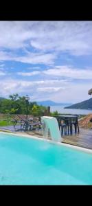 a swimming pool with a fountain and a table at Suítes mirante corumbê in Paraty