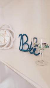 une étagère blanche avec un verre de vin et un ruban bleu dans l'établissement La Perla Blu, à Calasetta