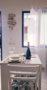 une table blanche avec deux chaises et une fenêtre dans l'établissement La Perla Blu, à Calasetta