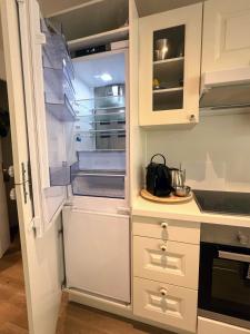 uma cozinha com armários brancos e um frigorífico aberto em Superbe appartement avec Terrasse Jardin et Parking privé em Saint-Tropez