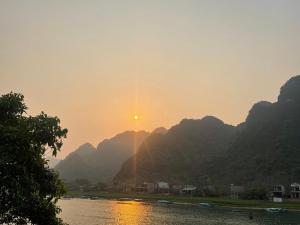 a river with the sun setting behind some mountains at Cornflower Homestay PHONG NHA in Phong Nha