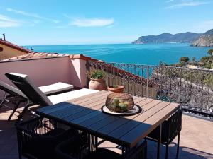 a table on a balcony with a view of the ocean at Alla Porta Rossa in Manarola