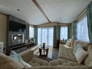ein Wohnzimmer mit einem großen Sofa und einem TV in der Unterkunft RJ Luxury caravan hire 2 with Hot Tub in Tattershall