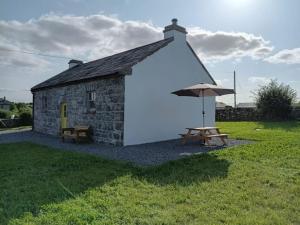 a small building with an umbrella and a picnic table at St Johns old Schoolhouse in Lecarrow