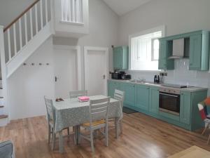 a kitchen with green cabinets and a table with chairs at St Johns old Schoolhouse in Lecarrow
