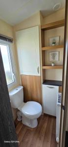 a small bathroom with a toilet and a window at RJ Luxury caravan hire 2 with Hot Tub in Tattershall