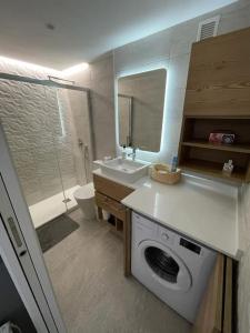 een badkamer met een wasmachine en een wastafel bij Apartamento muy cerca del mar, piscina, a/a, wifi y garaje. in Benicàssim