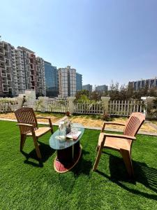 two chairs and a table on a grass field with buildings at AP's Castle Stay in Kharadi