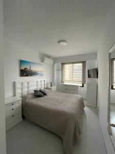 een witte slaapkamer met een bed en een raam bij Apartamento muy cerca del mar, piscina, a/a, wifi y garaje. in Benicàssim