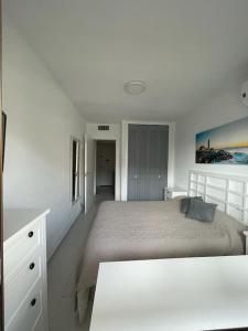 een witte slaapkamer met een bed en een dressoir bij Apartamento muy cerca del mar, piscina, a/a, wifi y garaje. in Benicàssim