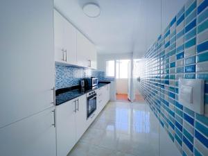 una cocina con armarios blancos y azulejos azules en la pared en Sunny Three bedroom apartment, en San Pedro del Pinatar