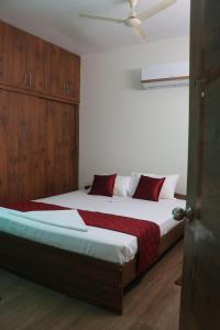 1 dormitorio con 1 cama grande con almohadas rojas en ROYAL RIDGE HOME STAYS, en Tirupati