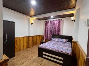 a bedroom with a bed and a window with purple curtains at Hangkhim Homestay in Ravangla