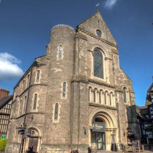 a large stone church with a clock tower at St Nicholas Boutique Hotel in Shrewsbury