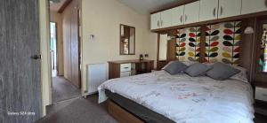 a bedroom with a large bed with a wooden headboard at RJ Luxury caravan hire 2 with Hot Tub in Tattershall