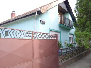 ein Haus mit einem roten Zaun davor in der Unterkunft Julija Pansion in Senta