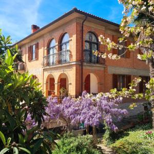 a brick house with purple flowers in front of it at Guest House San Francesco Garden in Rapolano Terme