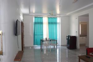 sala de estar con mesa y cortina azul en ROYAL RIDGE HOME STAYS, en Tirupati