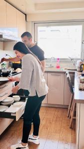 un uomo e una donna che preparano il cibo in una cucina di Sweet home near Paris with Eiffel Tower view & 1 cozy private room or entire apartment with 3 rooms a Courbevoie