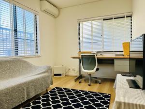 a bedroom with a bed and a desk with a computer at Accessible Four-Bedroom House near Kuzuha Station! in Hirakata