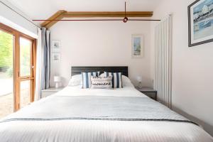 a bedroom with a large white bed and a window at Re-imagined Stone Barns in the Country Near the Coast in Padstow