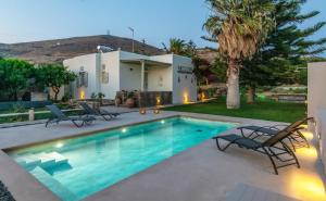 a swimming pool with chairs and a house at Windmill Villa in Tinos in Agios Sostis