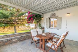 a patio with a wooden table and chairs at Windmill Villa in Tinos in Agios Sostis