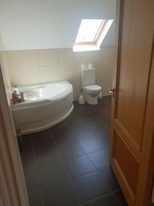 een badkamer met een bad, een toilet en een raam bij Green Acre in Tralee