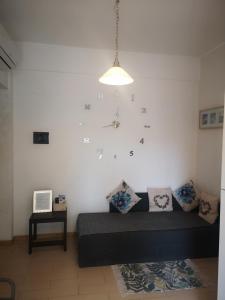 ElyCry B&b في Gli Angeli: غرفة معيشة مع أريكة وساعة على الحائط
