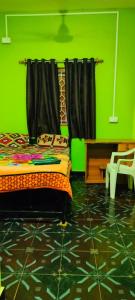 een groene kamer met een bed en een groene muur bij SriKrishna Guest House in Arambol