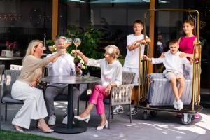 eine Gruppe von Menschen, die um einen Tisch mit einem Glas Wein sitzen in der Unterkunft Genusshotel Diamant in Naturns