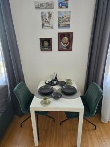 a white table with four chairs and plates on it at Apartman ured Tanja, Iver in Sesvete