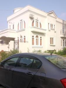 a car parked in front of a large white house at Royal Galaxy Bed & Breakfast E-11 Islamabad - For Families Only in Islamabad
