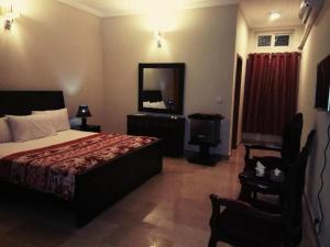 a bedroom with a bed and a mirror and a chair at Royal Galaxy Bed & Breakfast E-11 Islamabad - For Families Only in Islamabad
