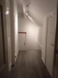 an empty hallway with a white wall and a wooden floor at Springhome Newport in Newport