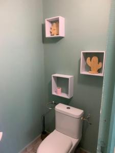 a bathroom with a toilet with two pictures on the wall at Rez de jardin Ylang Ylang in Saint-François