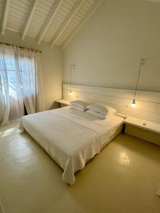 Un dormitorio con una gran cama blanca y una ventana en Villa Margarita, en Samos