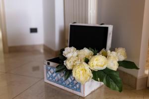 un vaso pieno di fiori bianchi seduto su un pavimento di Gioia Casa Vacanze by MONHOLIDAY a Monopoli