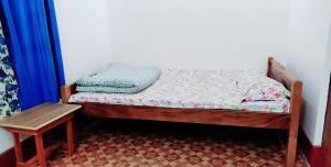 a small bed with a wooden frame and a table at India Tours Only Smriti Homestay in Rongli